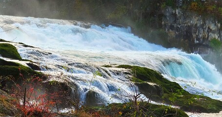 Vivid Natural Landscape Featuring Cascading Waterfall Surrounded By Vibrant Vegetation And Rocky Formations