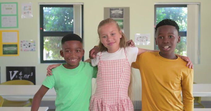 Diverse teenage students linking arms, responding to camera, high-fiving, posing at school by desks
