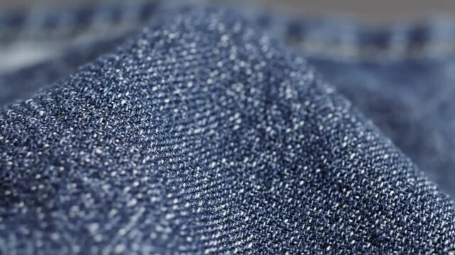 Close up view of blue denim fabric with visible texture and threads in macro detail