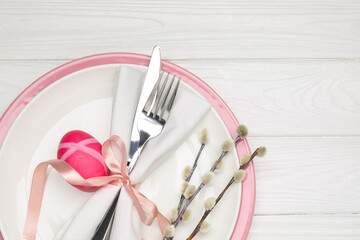 Festive table setting with Easter egg and willow branches on white wooden background, top view....
