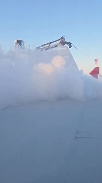Aircraft wing being deiced by specialized vehicle spraying anti-icing fluid to ensure safe flight in cold conditions. Vertical video
