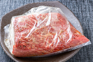 ローストビーフ調理シーン。牛ブロック肉と調味料をポリ袋に入れて下味をつける。