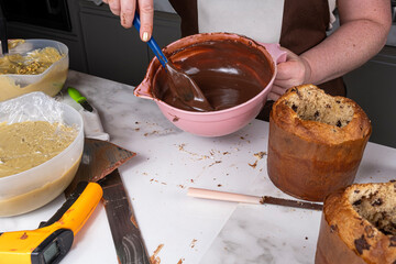 Confectioner with a bowl of melted chocolate for filling panettones.