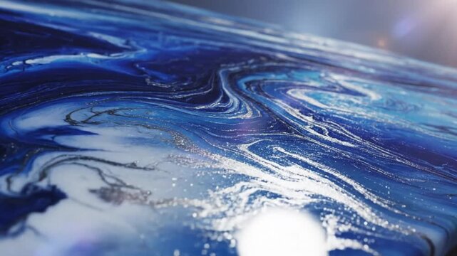 Abstract flowing blue and white epoxy resin art showing ocean wave patterns with swirling textures and silver shimmer