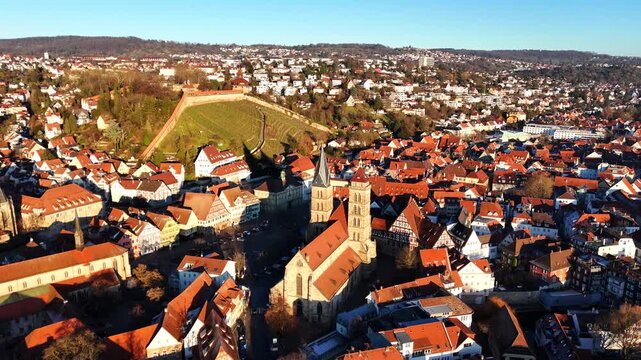 A broad panorama of Esslingen captures historic city buildings, church towers, red rooftops, trees, and a hillside in clear daylight. Suitable for travel, tourism, lifestyle, editorial, documentary