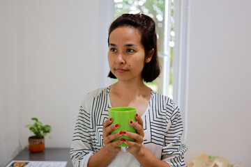 Woman boils water to make coffee to drink in the morning.