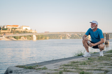 Senior athlete resting by river after workout, enjoying fitness and active lifestyle