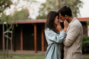 Romantic couple embracing in a garden near a wooden house