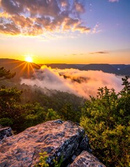 Mountain sunset view with clouds rolling over the forested hills, captured from a rocky outcrop