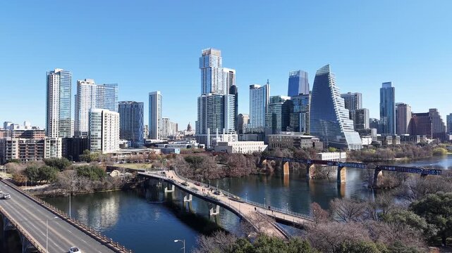 Austin Downtown and Skyline from Pfluger Pedestrian Bridge and MoPac Railroad Bridge over with Kayaks and Boats on Lady Bird Lake under Sunny Blue Sky