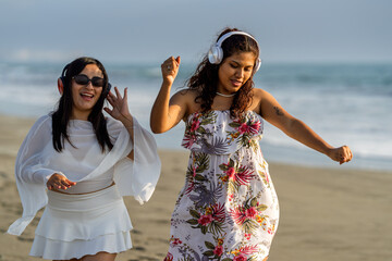 Young women enjoying music on beach at sunset