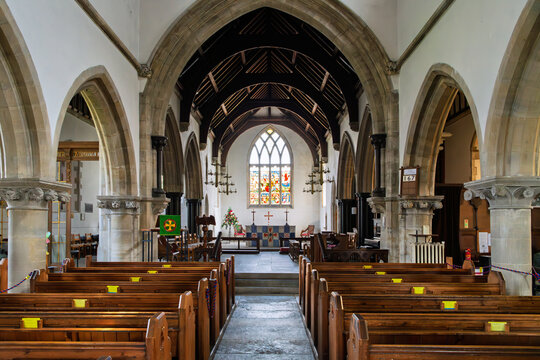 The interior nave, pews and altar of St Edward's Church, a medieval church dating back to Norman times in the village of Corfe Castle, England.
