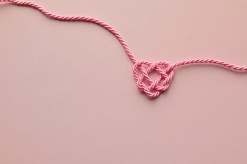 A charming heart made of pink rope on a pink background © LineDP