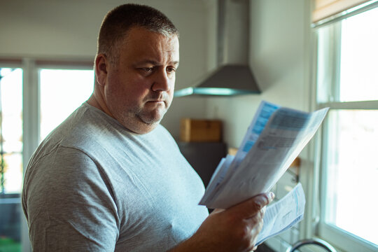 Middle aged man reviewing utility bills in home kitchen