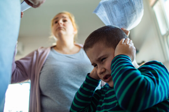 father and mom argue over bills at home while son covers ears