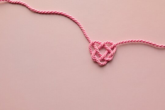 A charming heart made of pink rope on a pink background