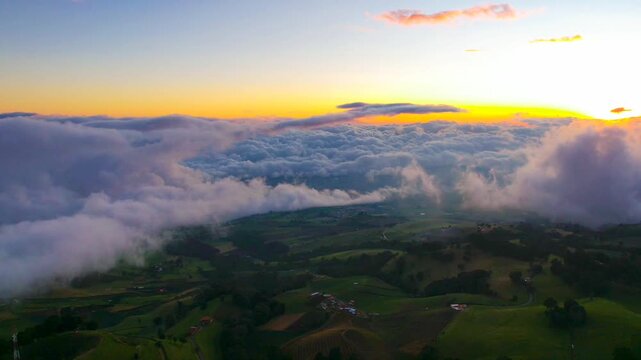Aerial Hyperlapse Over Rural Farmland Road Surrounded by Green Fields and Mountains Under Cloudy Sky
