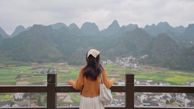 Young happy woman tourist enjoying the beautiful nature landscape with mountains while traveling in Wanfenglin in China, Wellness and travel concept