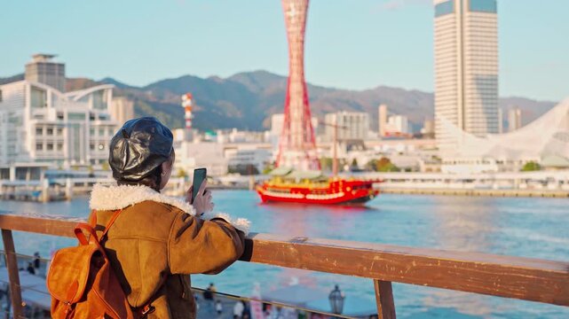 Young happy woman tourist enjoying the beautiful city landscape while traveling in Kobe port, Japan