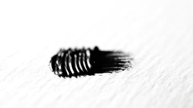 Black mascara application on white paper showing texture and precision details macro close-up