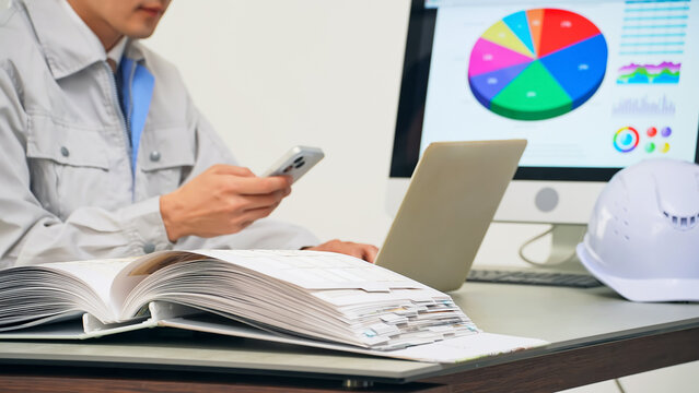 A male worker working in the office using a PC and smartphone
