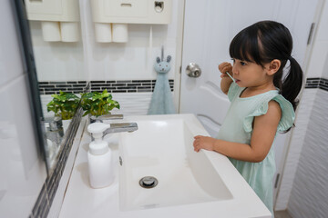 girl child brushing teeth in bathroom