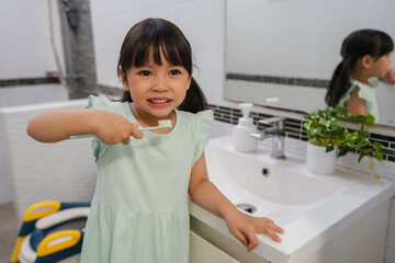 girl child brushing teeth in bathroom