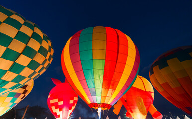 colorful hot air balloons glowing against dark night sky