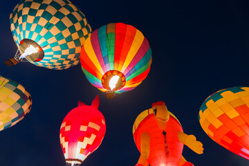 colorful hot air balloons glowing against dark night sky