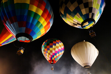 colorful hot air balloons glowing against dark night sky
