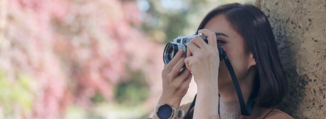 Banner Asian photographer tourist using DSLR professional camera travel on vacation. Female young traveler take a photo camera outdoors. Banner woman backpack travel photographer with copy space