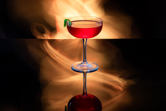 Beautiful cosmopolitan cocktail garnished with a lime twist with dramatic light painting for the background