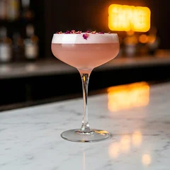 Wandcirkels Bar  frothy, pale pink French Martini in a vintage coupe glass, sprinkled with dried rose petals.  is taken from a low angle on a white marble bar top, with the warm glow of a distant neon sig  © ❤  Nancyvoz68❤ 