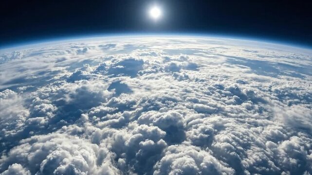 An breathtaking aerial perspective captures a majestic expanse of fluffy white clouds stretching across the globe. The deep blue curve of the planet's atmosphere meets the vast, dark emptiness of spac