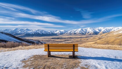 Fototapeta premium Wooden park bench faces expansive vista of snowcapped mountains under brilliant blue sky