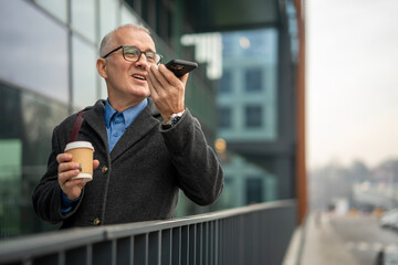 Mature man conversing on smartphone holding coffee cup