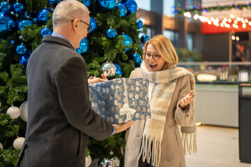 Mature man surprising woman with christmas gift