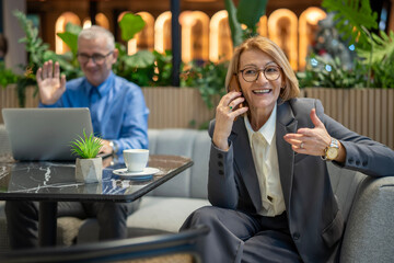 Senior businesswoman talking on phone with man on video call