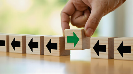 Wooden blocks arranged in a row with one block flipped to show a green arrow pointing right, symbolizing change and direction