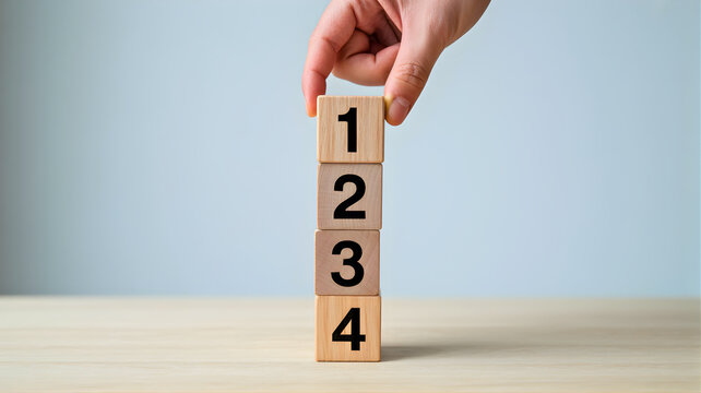 Person's hand carefully placing the first numbered wooden block on a stack, symbolizing a structured process, sequential steps, or strategic planning for business success and achievement