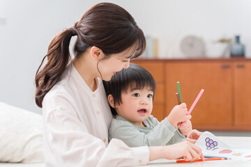 家でお絵描きする子供とママ