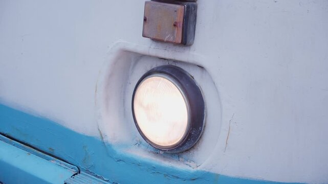 Round flickering headlight of an old bus close-up