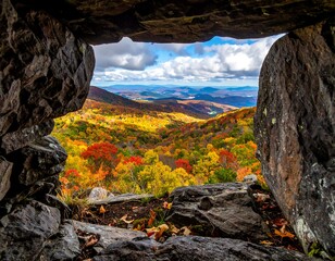Autumnal vista framed by a rugged stone opening, showcasing a vibrant mountain landscape of fall foliage and a cloudy sky