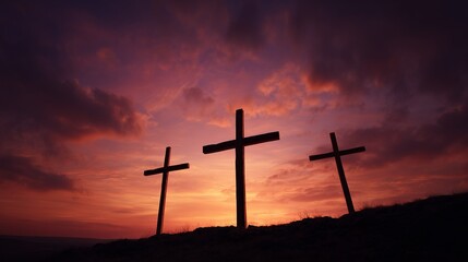 Three silhouettes of crosses on hill against dramatic sunset sky