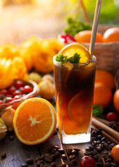 Vertical shot of iced black coffee mixed with orange juice, topped with fresh parsley and orange slice in a cafe atmosphere