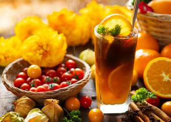 Iced americano orange coffee in a glass decorated with fresh orange slice, cinnamon, and coffee beans on wooden table