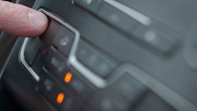 Close up of finger pressing car climate control button on modern vehicle dashboard. Concept of car heating and comfort driving in winter season
