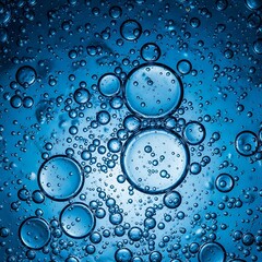 Spherical transparent fluid forms suspended within a luminous blue liquid display detailed surface tension.