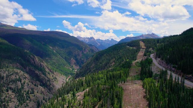 Aerial view over mountain road between Silverton, CO and Molas Pass. Shows lush, green forest and impressive mountains along with the Animas River in the canyon below. Beautiful summer day.