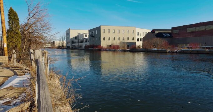 Handheld Shot of Old Historic Paper Mill Buildings alongside walking path on a clear winter day, Fox River Appleton, Wisconsin